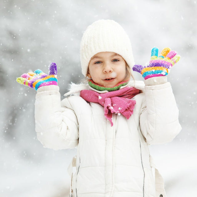 Gyermek téli szett: színes sapka, vastag sál és puhakezes kesztyű, havas háttérrel.